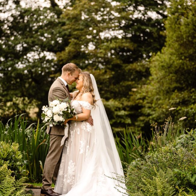 Bride and groom in a beautiful graden. Bride holding a white and green wedding bouquet.