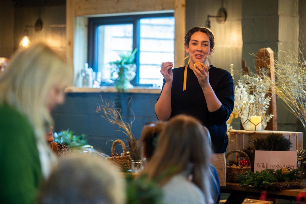 Floral Designer from Wildlings & Aster teaching guests how to make their own Christmas door wreath.