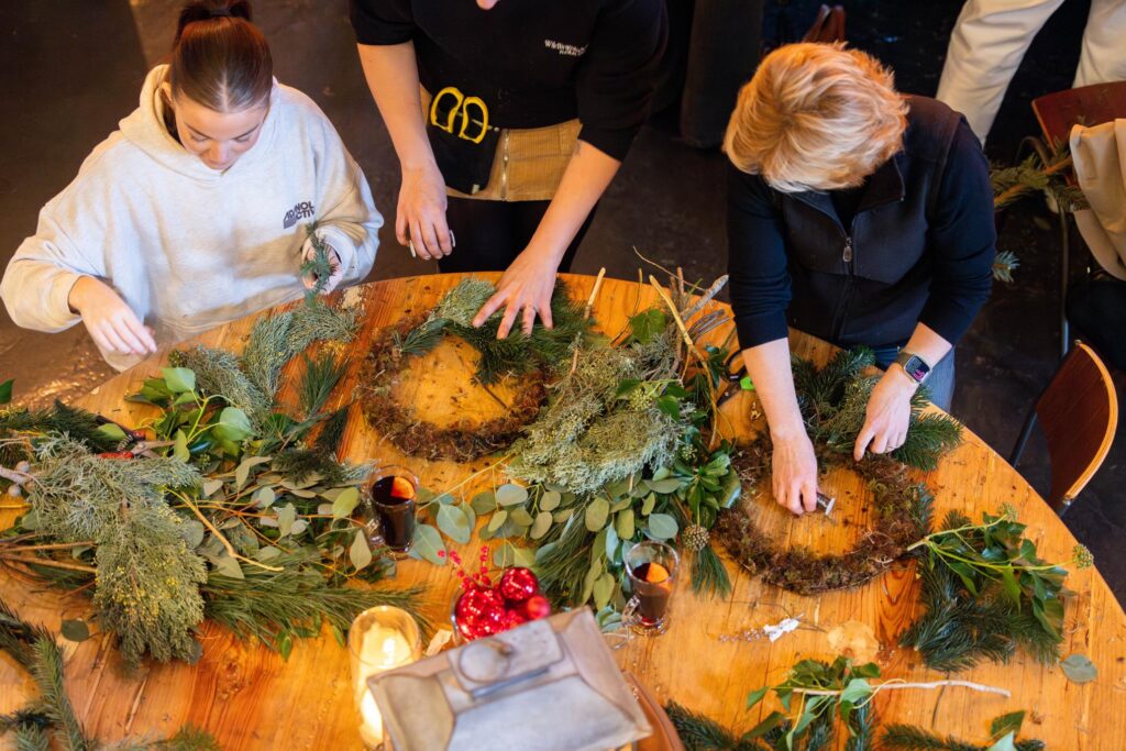 Floral designer teaching guests how to make their own Christmas Door wreaths.